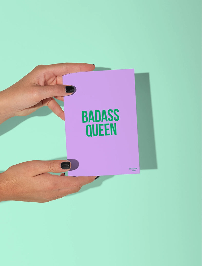 Carte postale mauve tenue par deux mains, avec le texte vert "Badass queen"