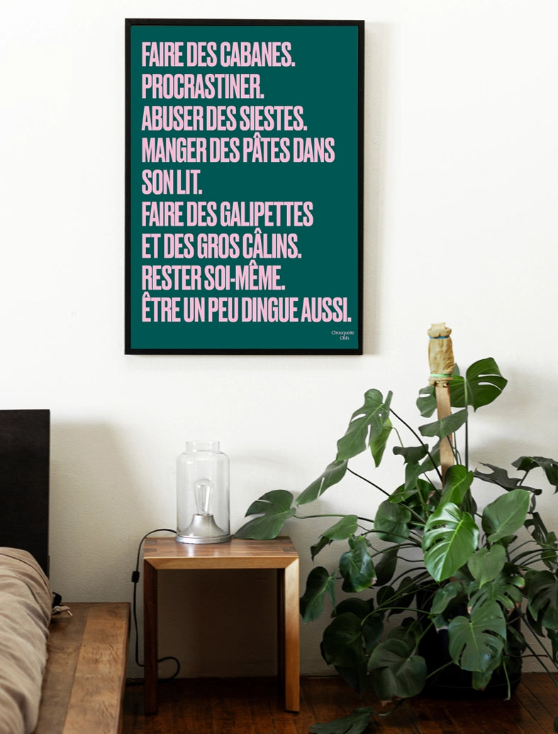 poster chouquette club vert sapin avec un mantra écrit dessus en rose dans un cadre en bois noir dans un chambre avec une plante