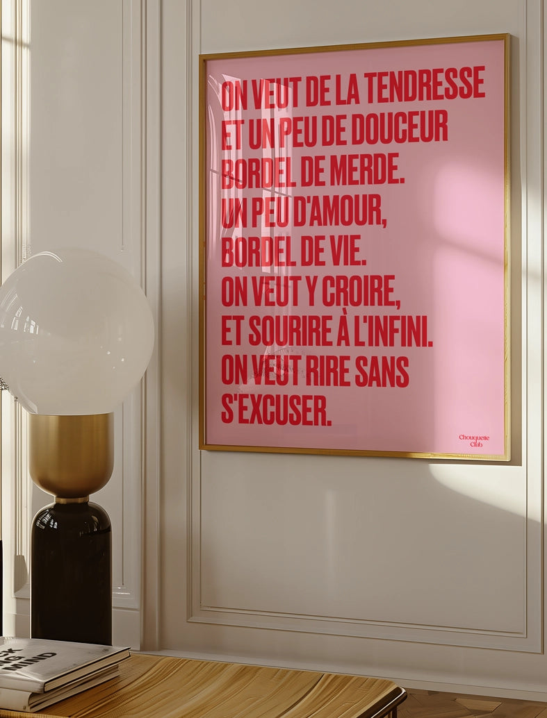 poster avec un mantra écrit dessus en rose et rouge dans un cadre en bois, dans un salon avec une lampe