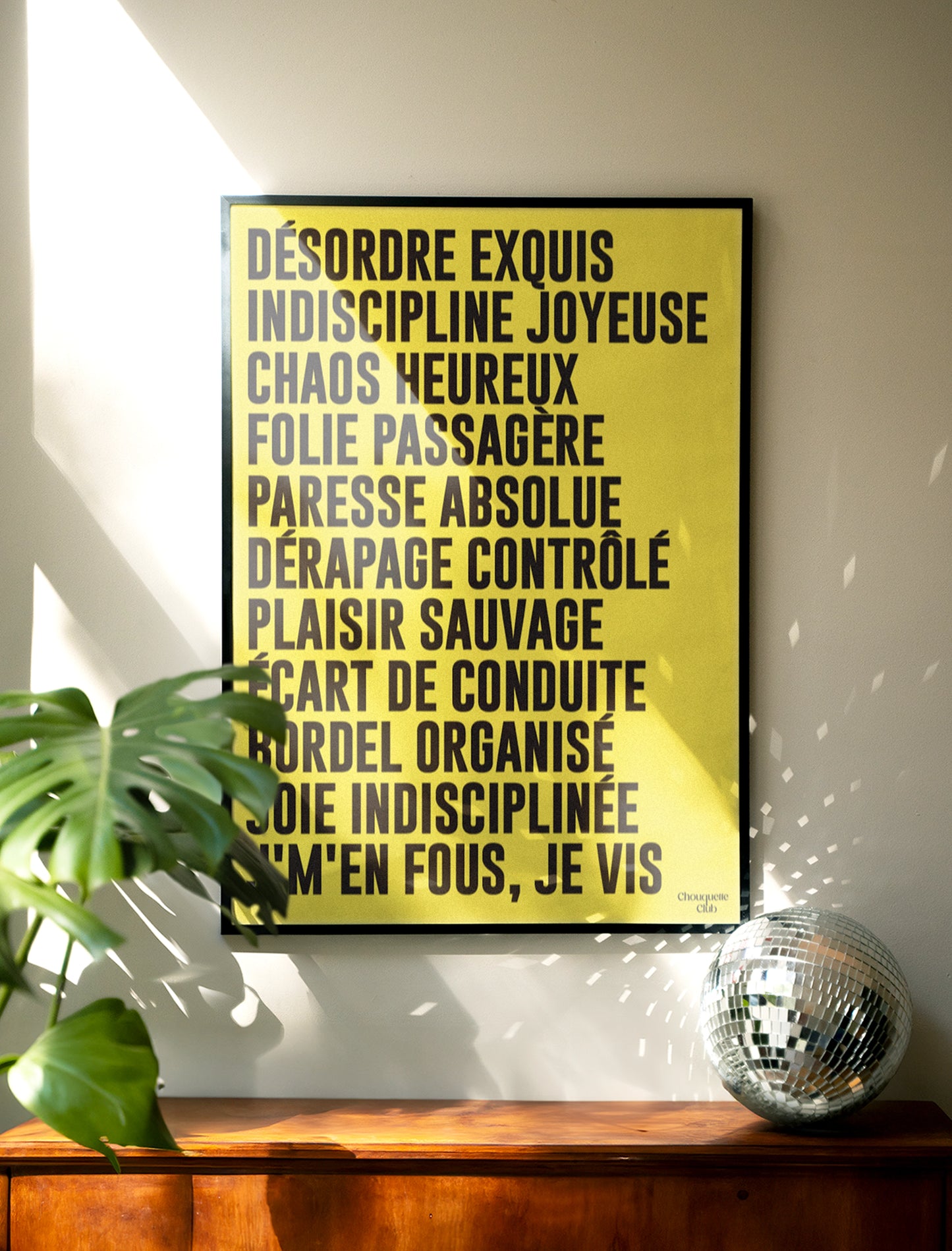 poster mantra ecrit en noir sur fond jaune de chez chouquette club accroché au mur avec une boule à facette