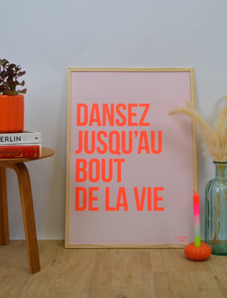 Poster "Dansez jusqu’au bout de la vie" avec Orange fluo dans un cadre en bois posé au sol sur du parquet