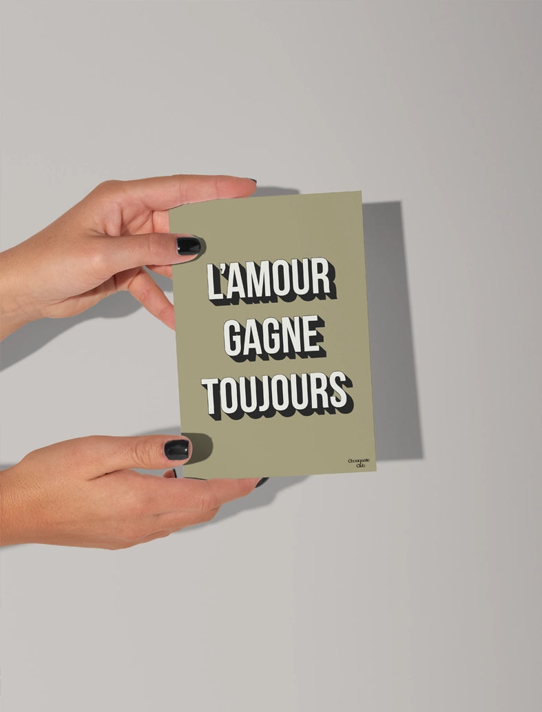 mains qui tiennent une carte postale "L'amour gagne toujours carte postale "