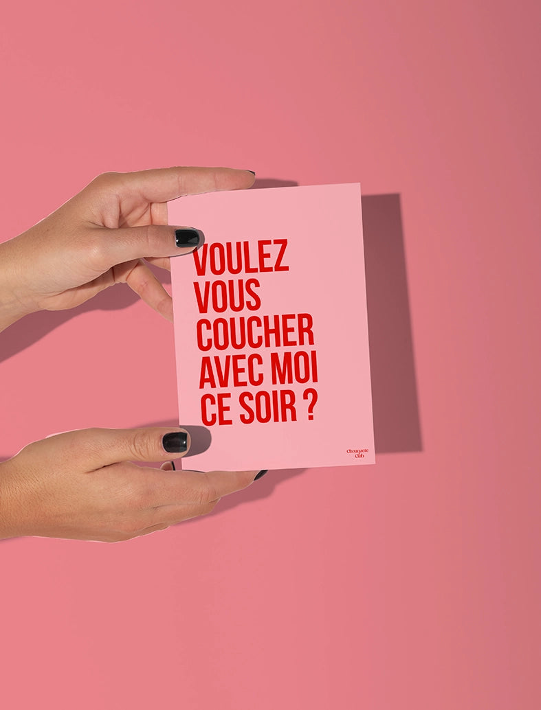 Mains tenant une carte postale rose écrit en rouge "Voulez-vous coucher avec moi ce soir?"