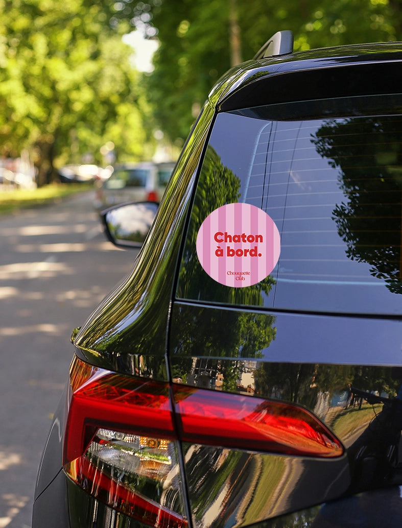 Sticker « Chaton à bord » rayures rose et rouge collé sur une voiture