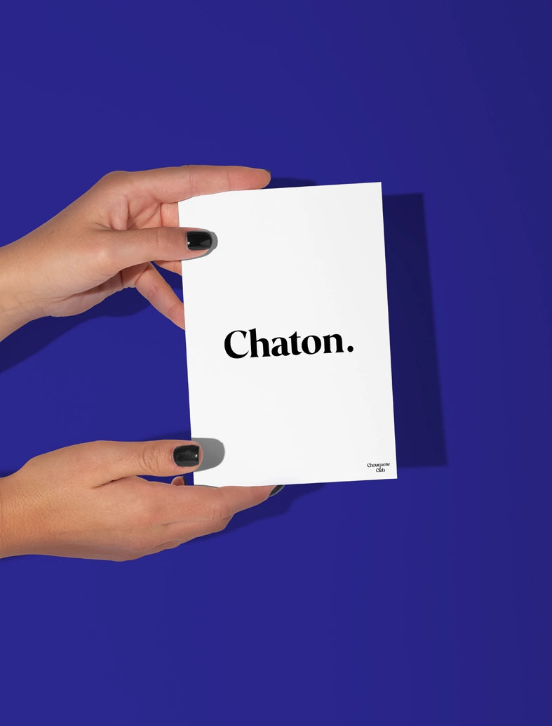 Deux mains qui tiennent une carte postale écrit chaton en noir et blanc