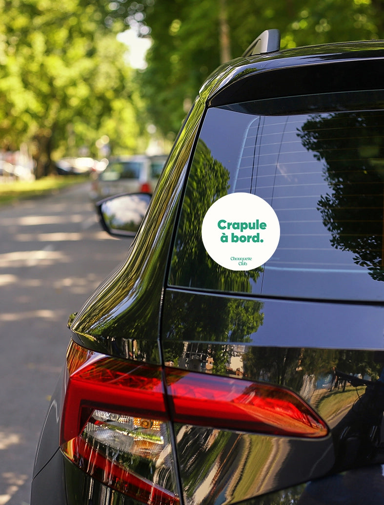 Sticker « Crapule à bord » vert et blanc collé sur une vitre arrière de voiture