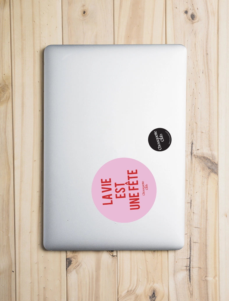Sticker « La vie est une fête » rose et rouge collé sur une façade d' ordinateur