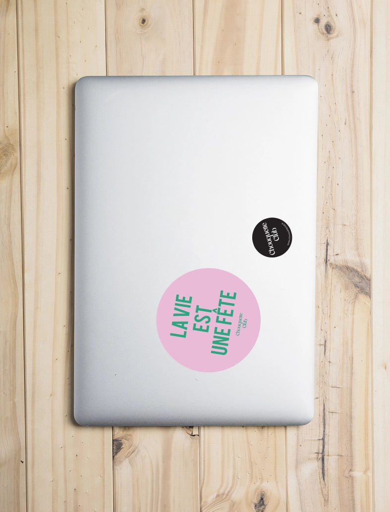 Sticker « La vie est une fête » rose et vert collé sur un ordinateur