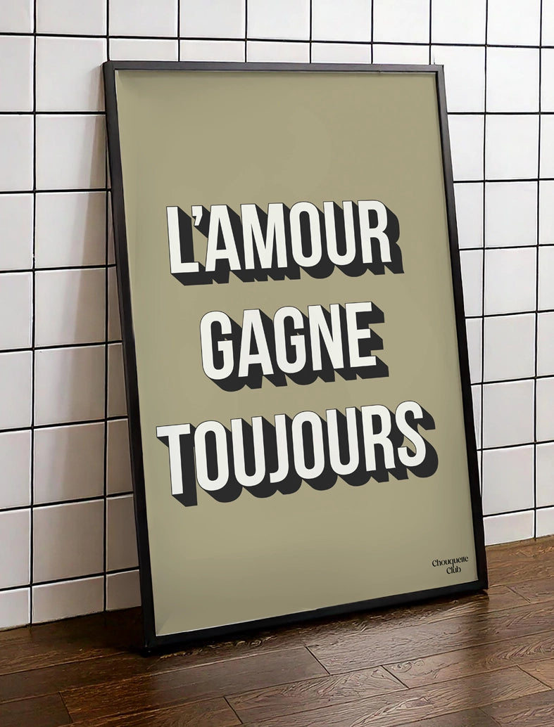 Affiche "L'amour gagne toujours" de Chouquette Club encadrée posée sur du parquet