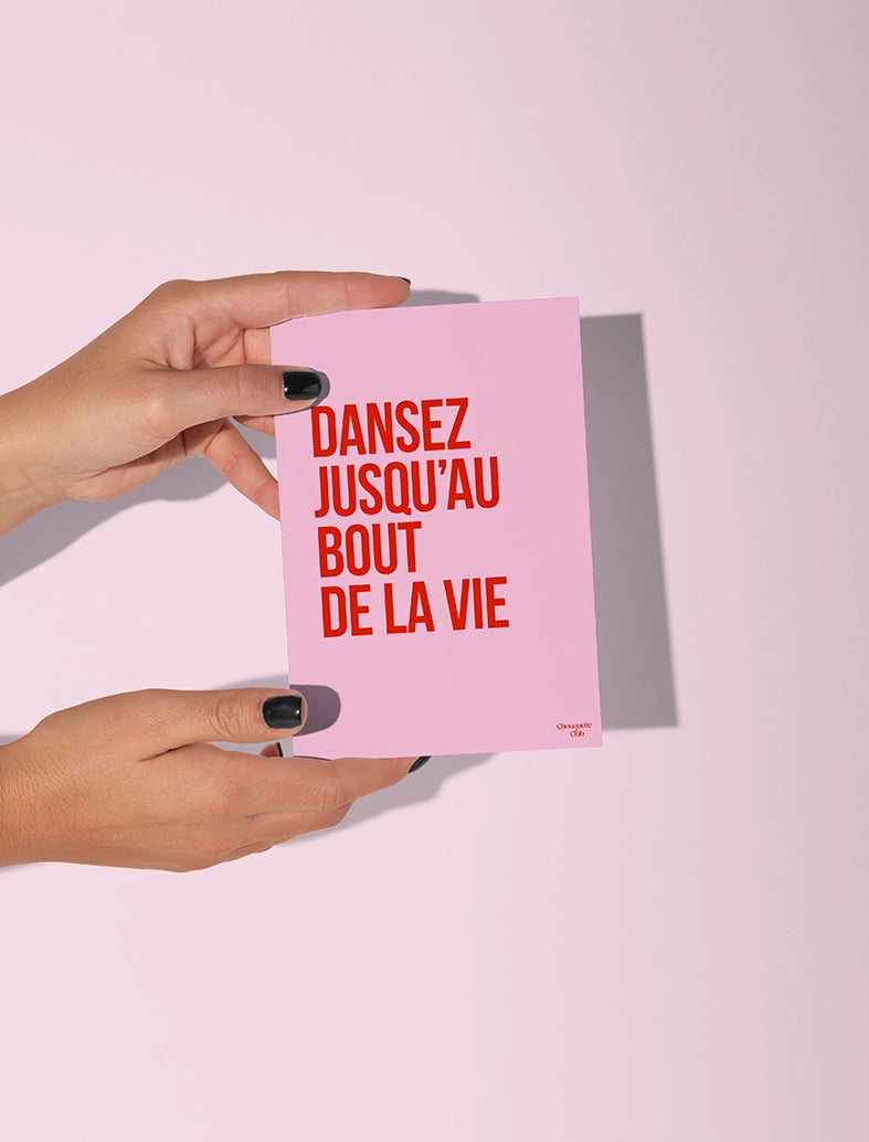 Carte postale rose tenue par deux mains, avec le texte "Dansez jusqu'au bout de la vie rose et rouge"