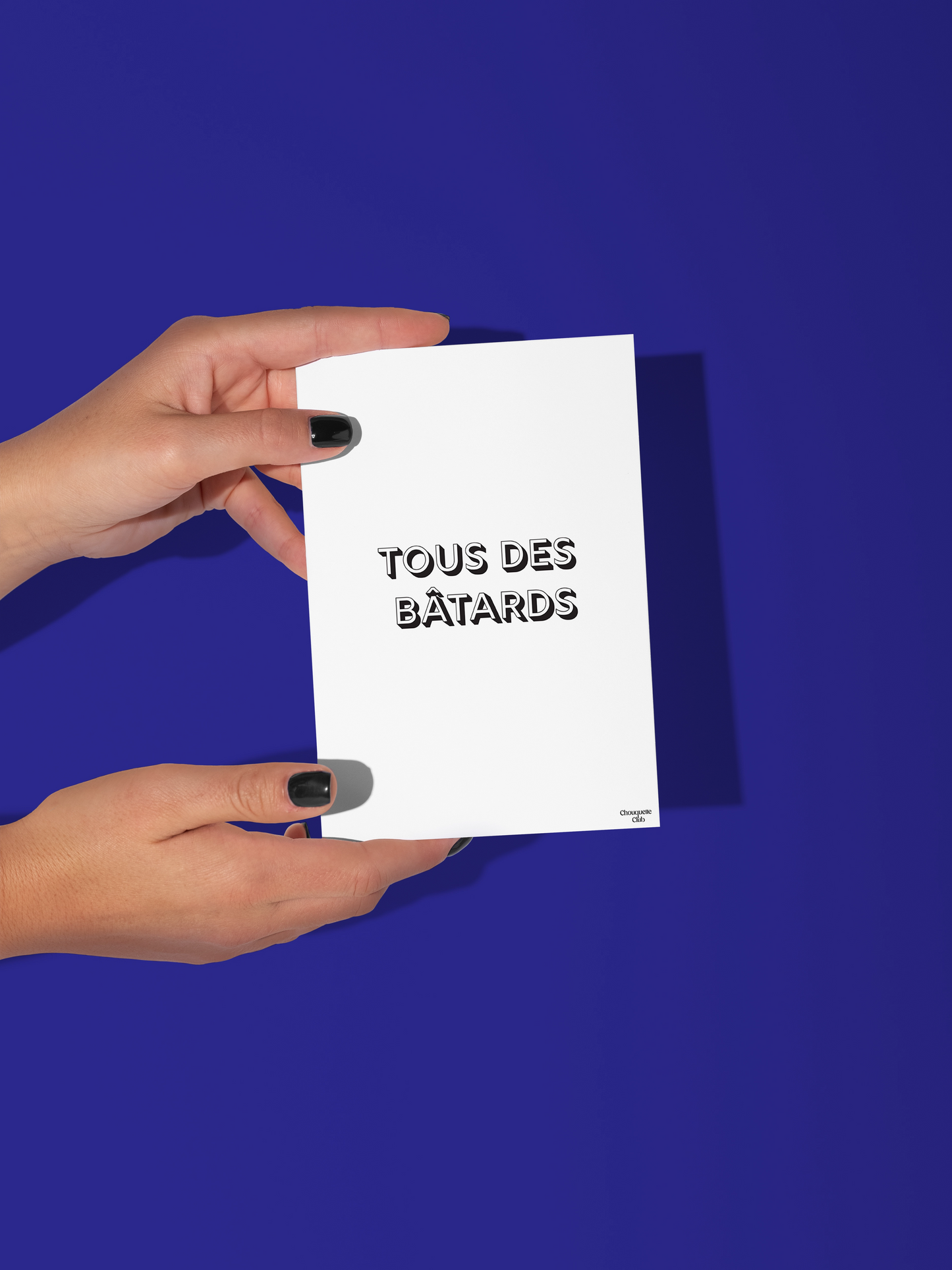 Carte postale noir et blanc écrit "Tous des bâtards" tenue par deux mains
