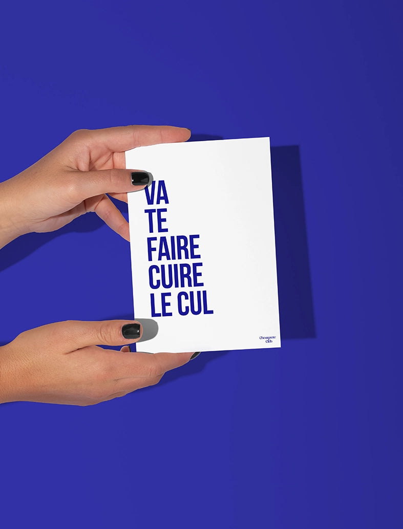 Deux mains qui tiennent une carte postale blanche avec écrit dessus "Va te faire cuire le cul " en bleu