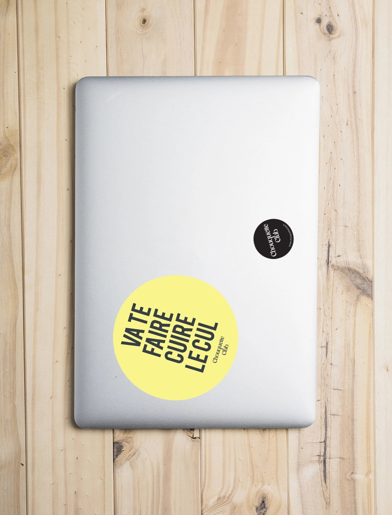 Sticker « Va te faire cuire le cul » jaune collé sur un laptop