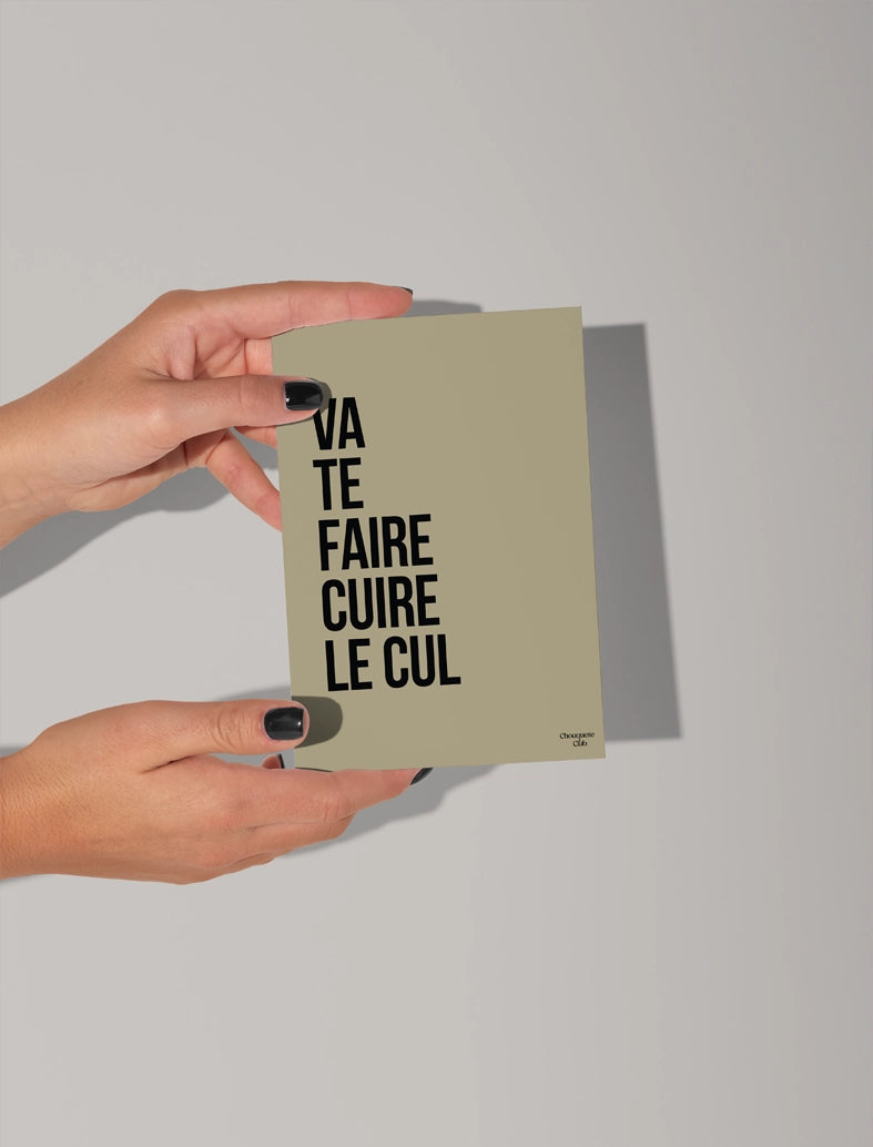 Deux mains qui tiennent une carte postale avec écriture en noir dessus “Va te faire cuire le cul ” fond kaki