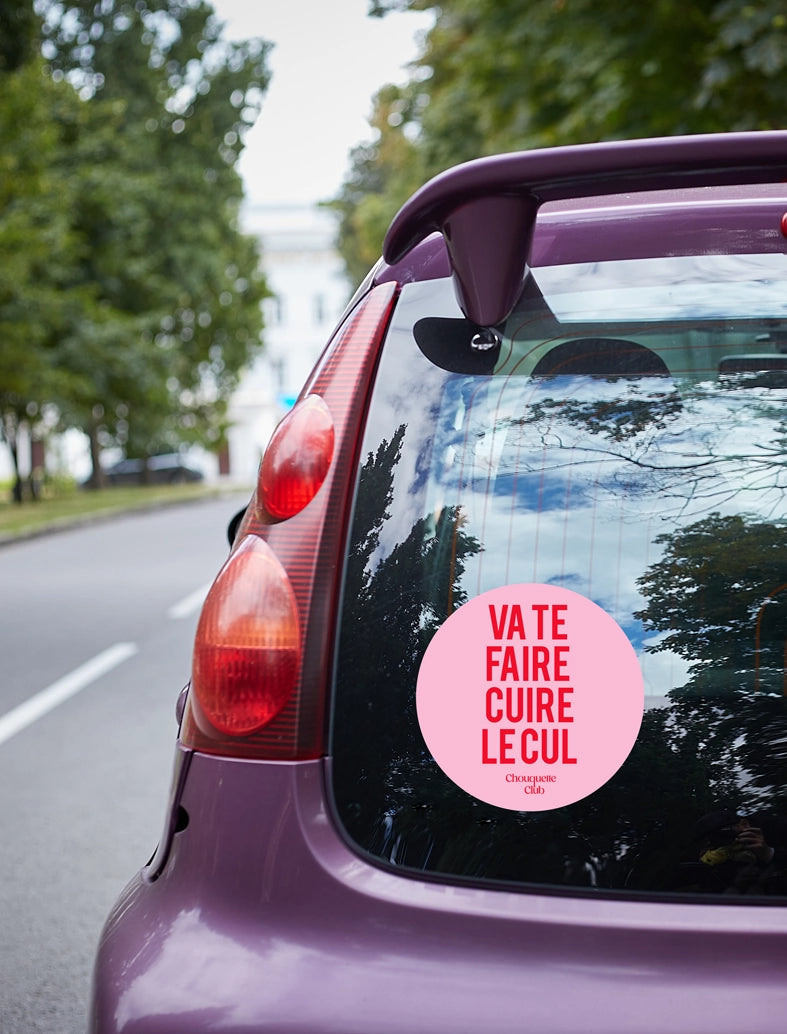 Sticker « Va te faire cuire le cul » rouge et rose collé sur une voiture