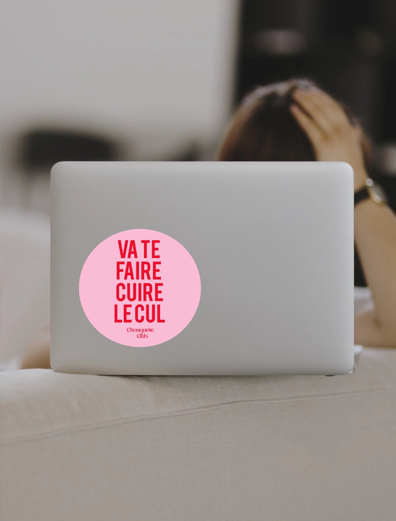 Sticker « Va te faire cuire le cul » rouge et rose collé sur un ordinateur