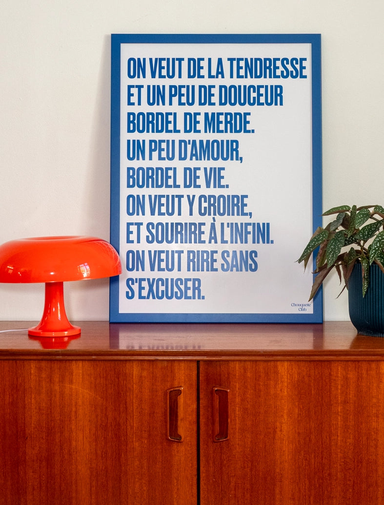 poster avec un mantra écrit dessus en bleu dans un cadre en bois bleu, dans un salon avec une lampe orange