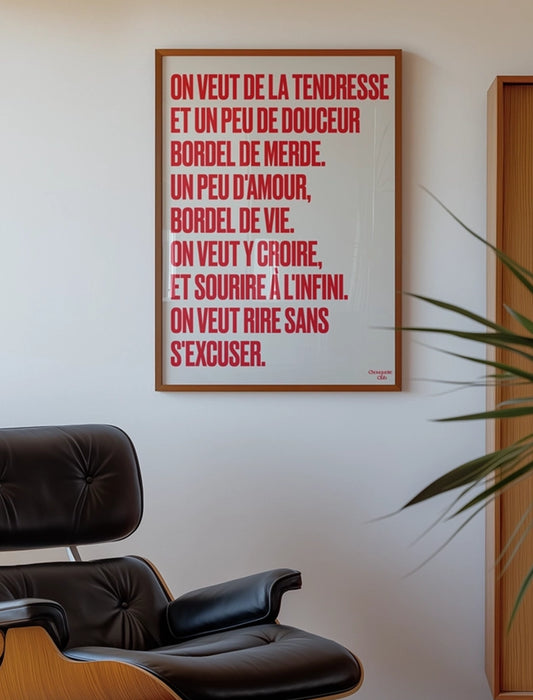 poster avec un mantra écrit dessus en rouge dans un cadre en bois, dans un salon avec fauteuil en cuir vintage