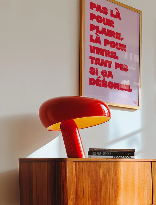 poster avec un mantra écrit dessus en rose et rouge dans un cadre en bois, dans un salon avec une lampe rouge