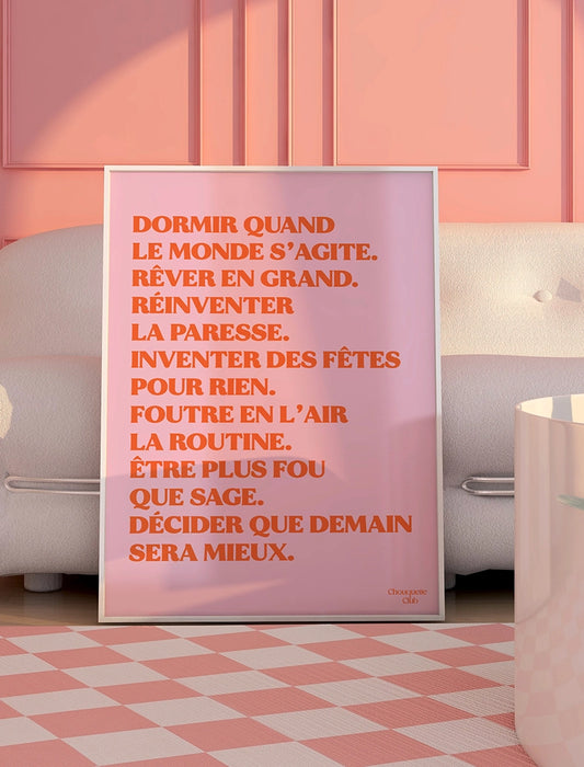 Mantra rose et orange encadré de la marque Chouquette Club posé au sol dans un salon.