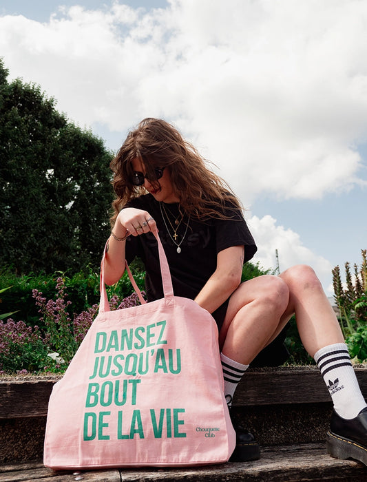 sac en coton rose et vert de chouquette club marqué dessus "dansez jusqu'au bout de la vie" avec une jeune fille aux cheveux longs et ondulés bruns
