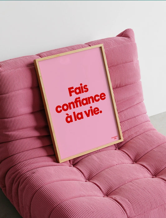 Affiche encadrée avec comme punchline "Fais confiance à la vie affiche (rose et rouge)" sur un fauteuil rose