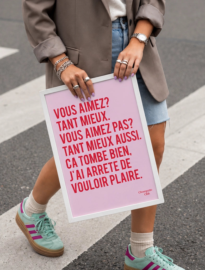 J'ai arrêté de vouloir plaire affiche rose et rouge encadré et tenu par une jeune fille sur un passage piéton
