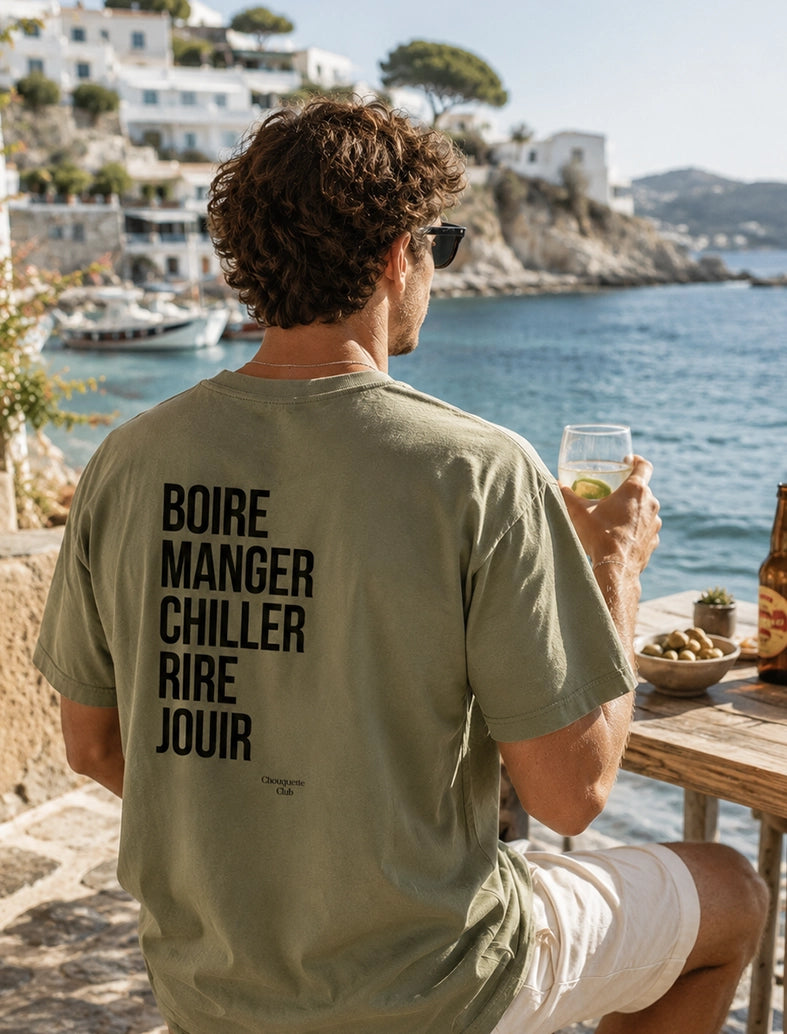 Tee-shirt homme "Boire manger chiller rire jouir" kaki porté par un homme face à la mer
