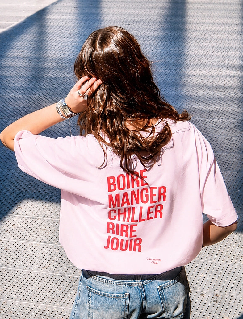 Tee-shirt femme "Boire manger chiller rire jouir" rose porté par une jeune fille brune