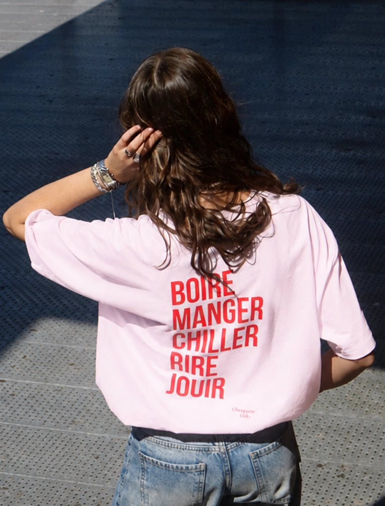 Tee-shirt femme "Boire manger chiller rire jouir" rose porté par une jeune fille brune
