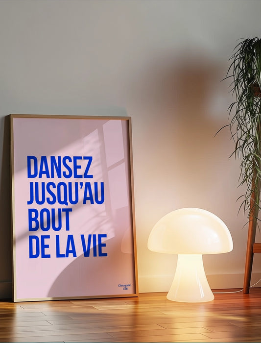 Dansez jusqu'au bout de la vie affiche (bleu électrique et rose pâle) de Chouquette Club posée au sol à côté d'une lampe