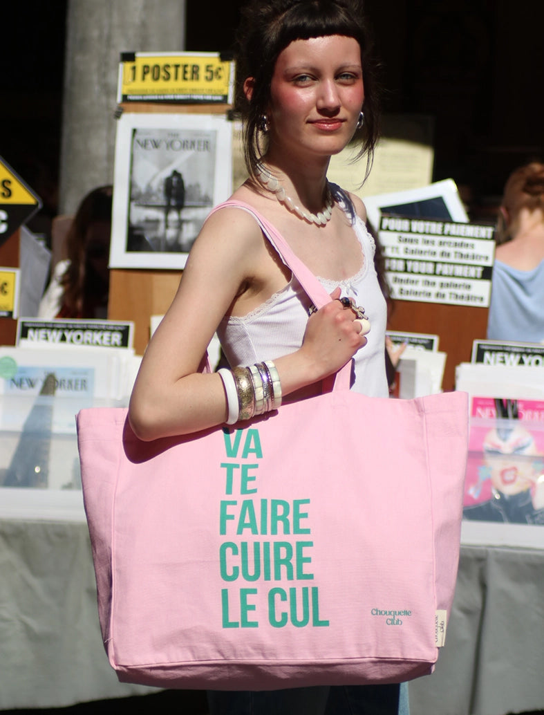 Tote bag XL en coton bio "Va te faire cuire le cul" rose et vert porté par une jeune fille brune