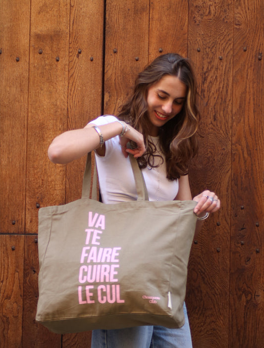 sac en coton kaki et rose de chouquette club marqué dessus "va te faire cuire le cul" porté par une jeune fille brune
