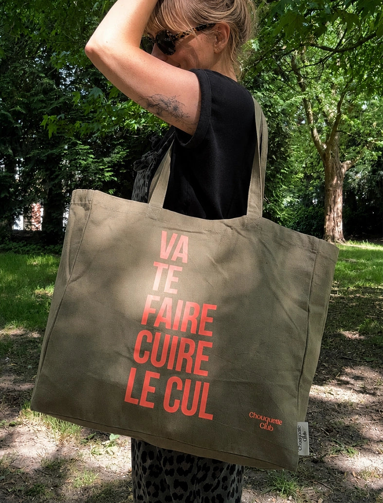 Tote bag XL en coton bio "Va te faire cuire le cul" kaki et corail fluo porté par une femme blonde
